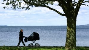 Image for our article about keeping a baby safe in hot weather, the image is of a mother walking with a sunshade on a pram